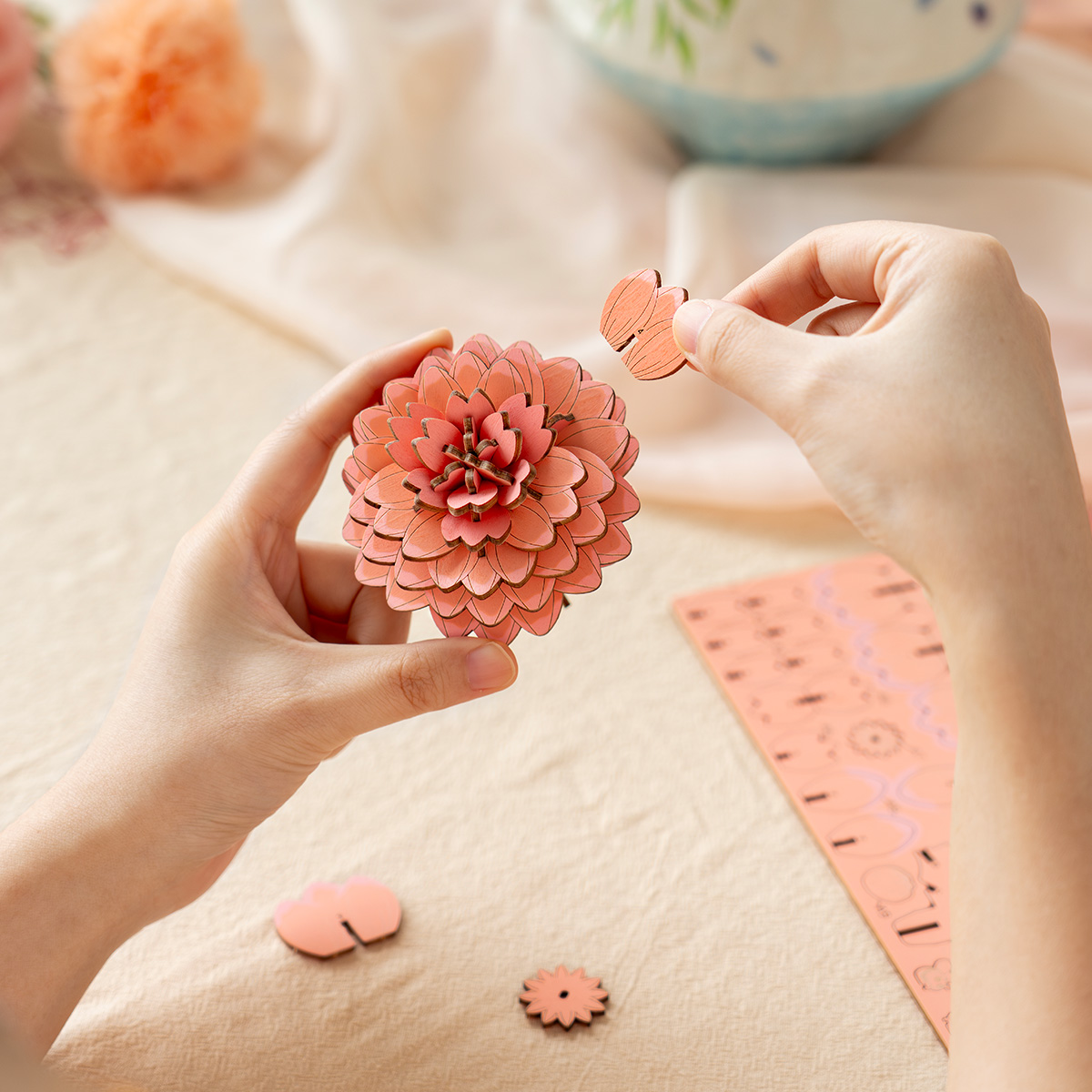Pink Dahlia TW131 assembly scene with hands arranging the wooden flower