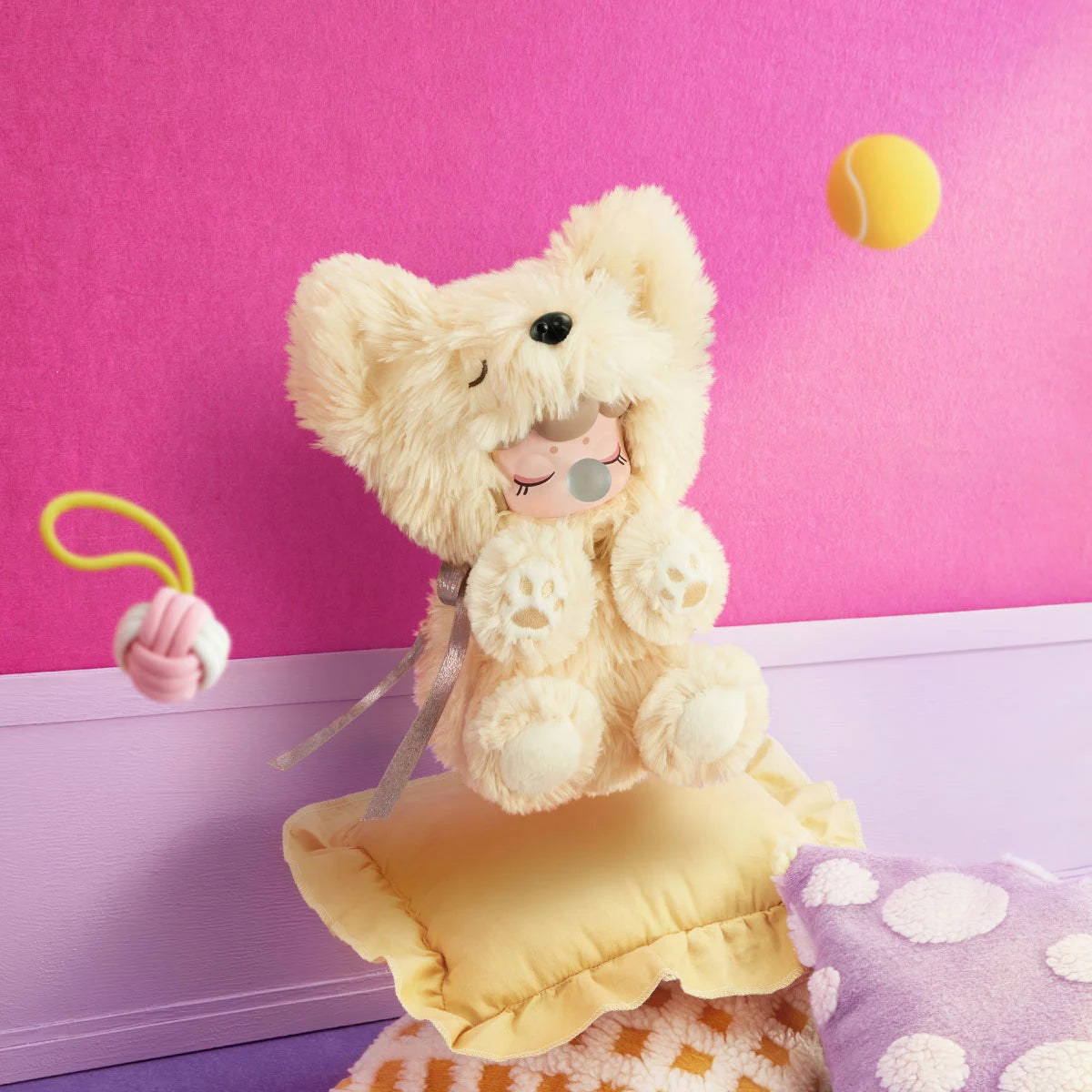 Cream Nanci Puppy Club Yorkie plush doll sitting on a yellow ruffled cushion against a pink wall, showing fluffy pointed ears, a sleeping face, blue bubble and paw pads.