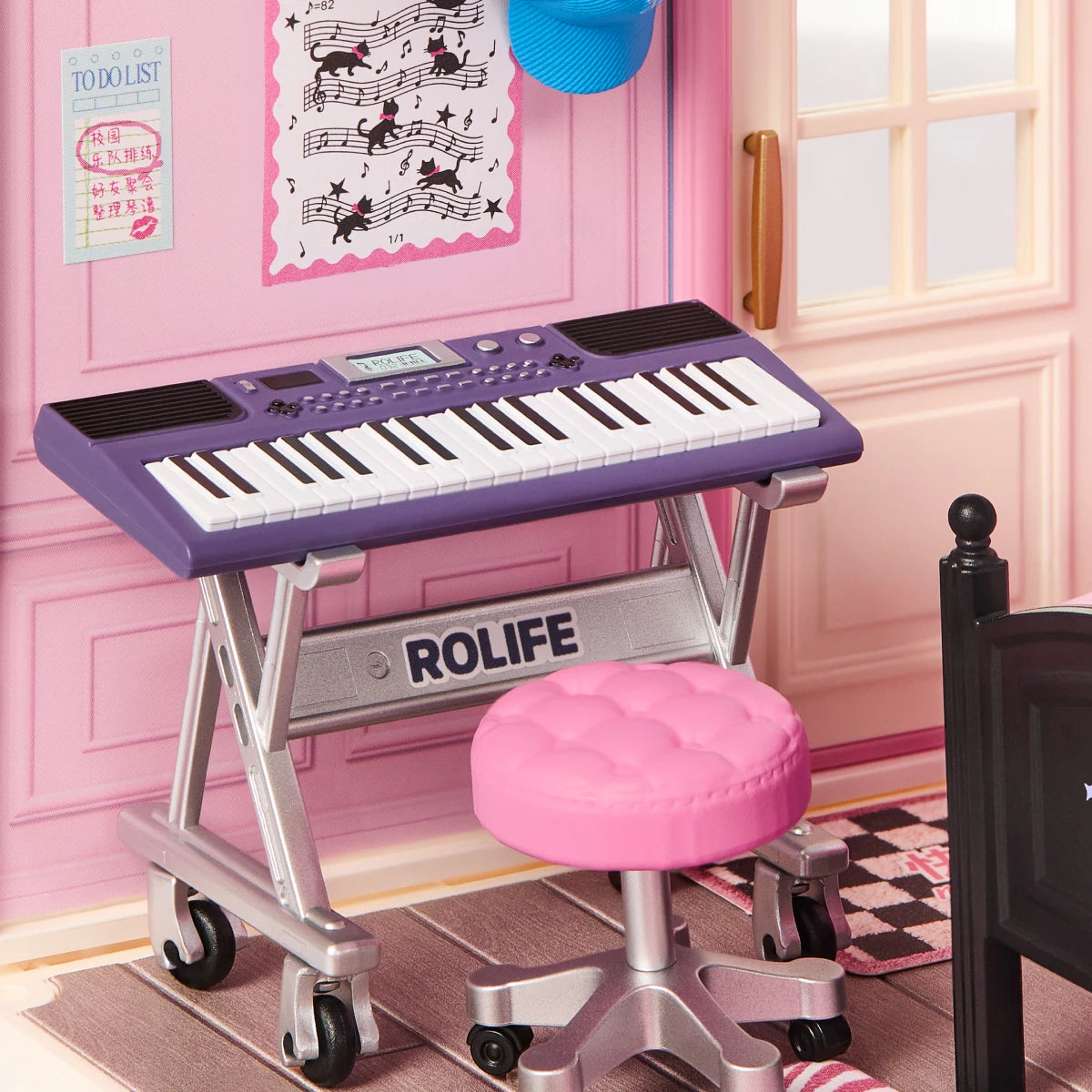 Miniature purple electronic keyboard on a silver folding stand with a pink cushioned stool, set in a pink room with a to-do list and cat music poster.