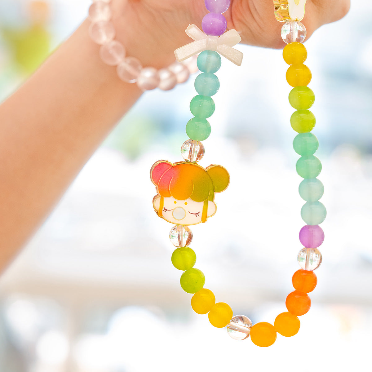 Nanci Sweet Time lanière de téléphone colorée en perles tenue dans la main