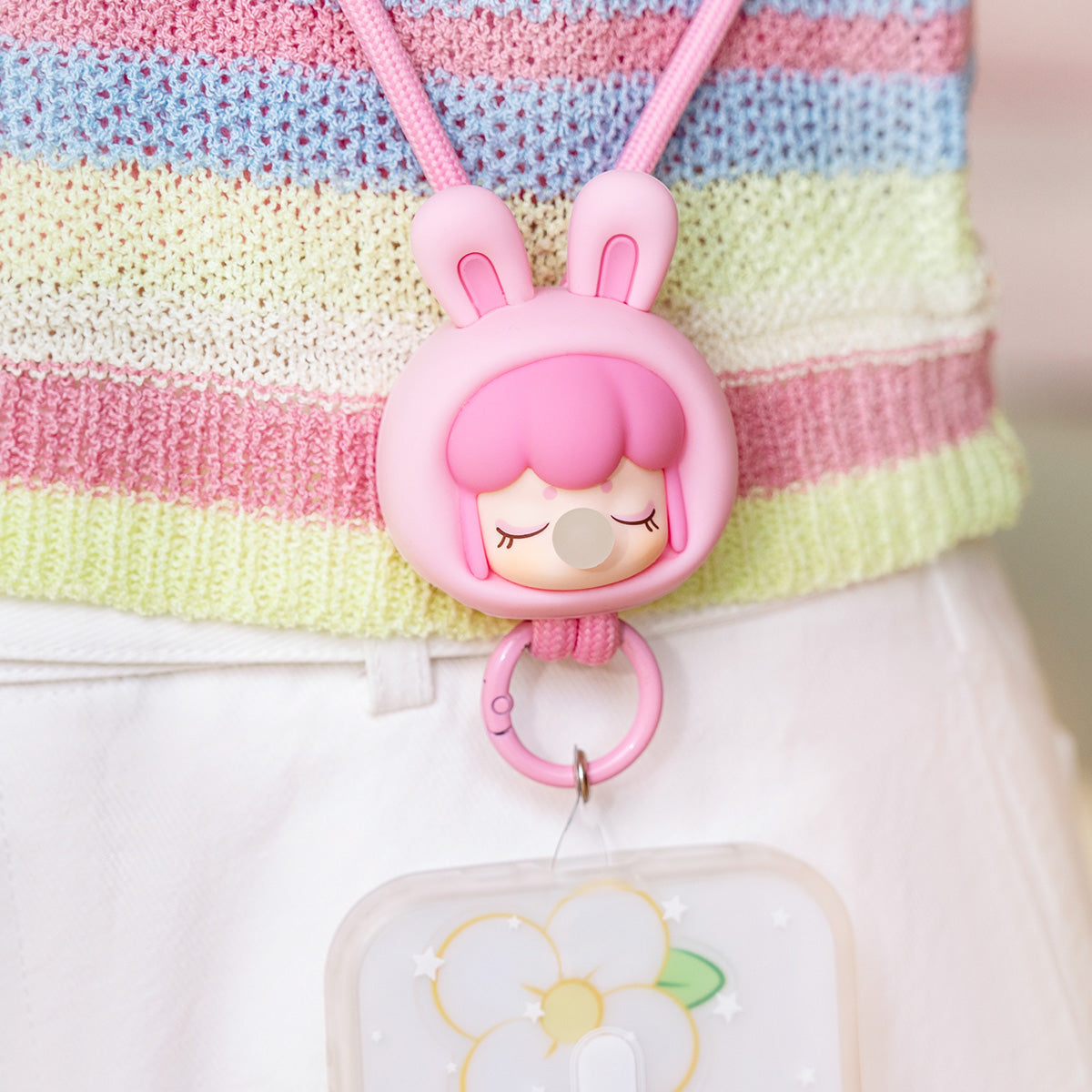 Baby Nanci Fluffy Party pink bunny phone chain hanging from a striped bag
