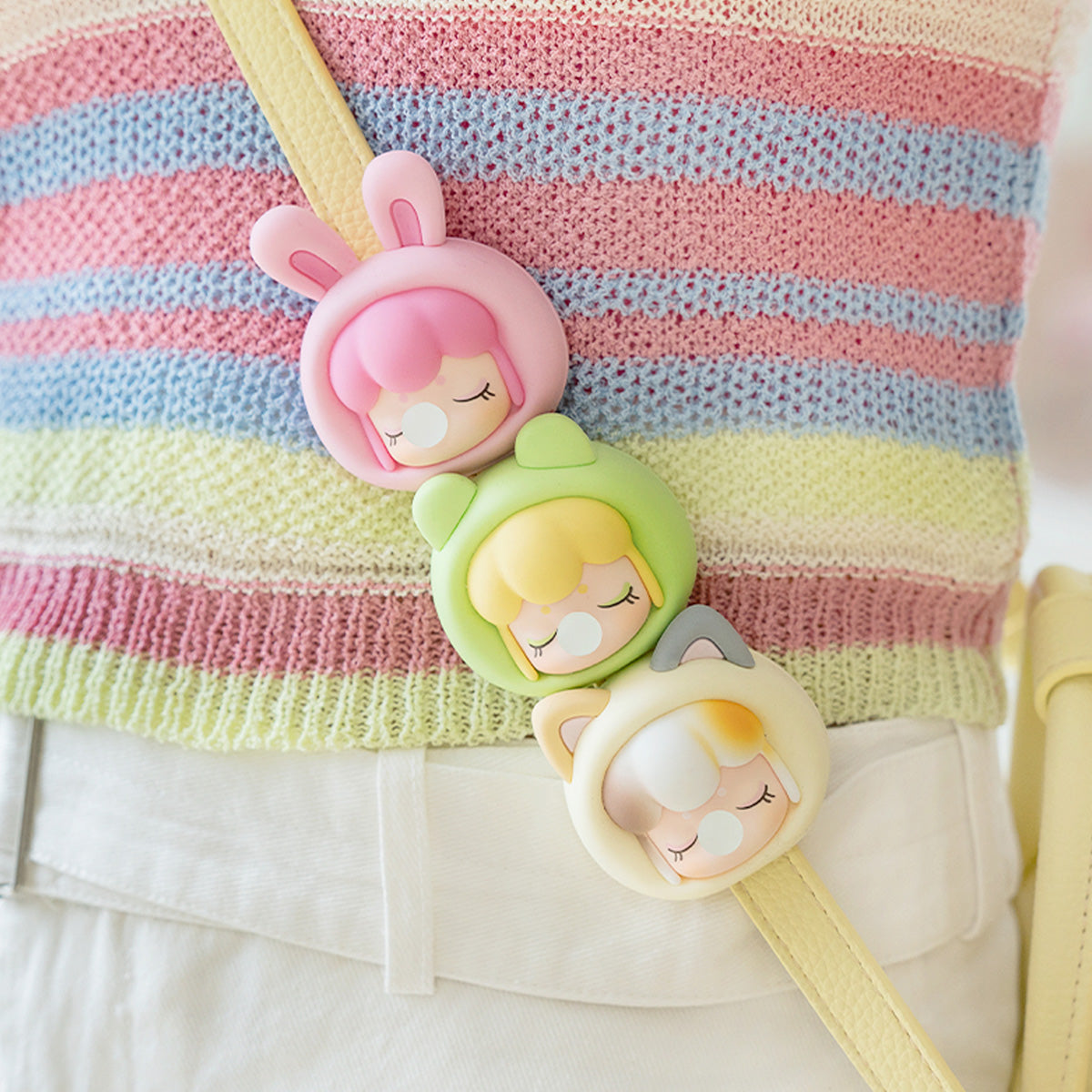 Baby Nanci Fluffy Party three phone chains hanging together from a striped bag