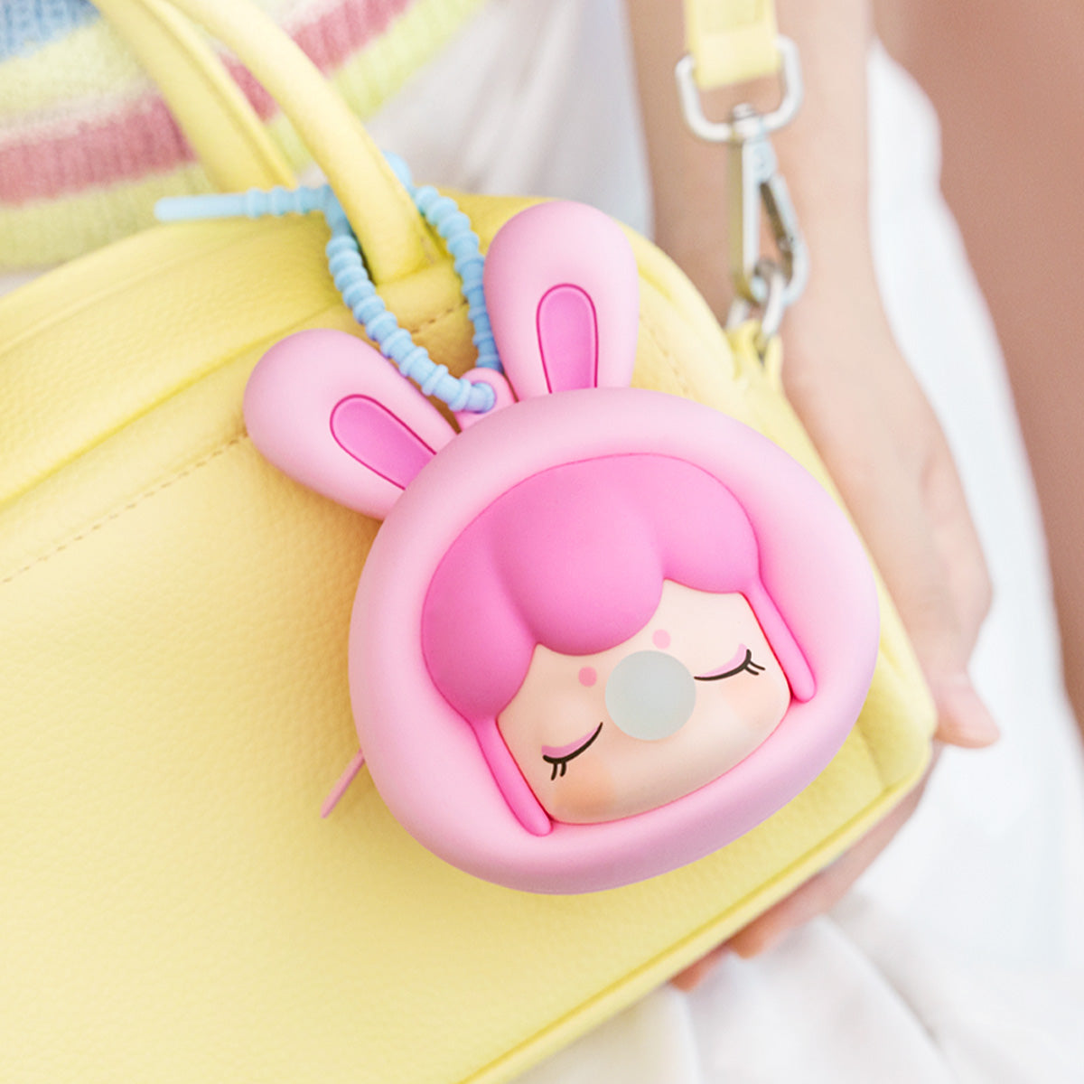 Funda de auriculares Baby Nanci Fluffy Party colgando de un bolso amarillo