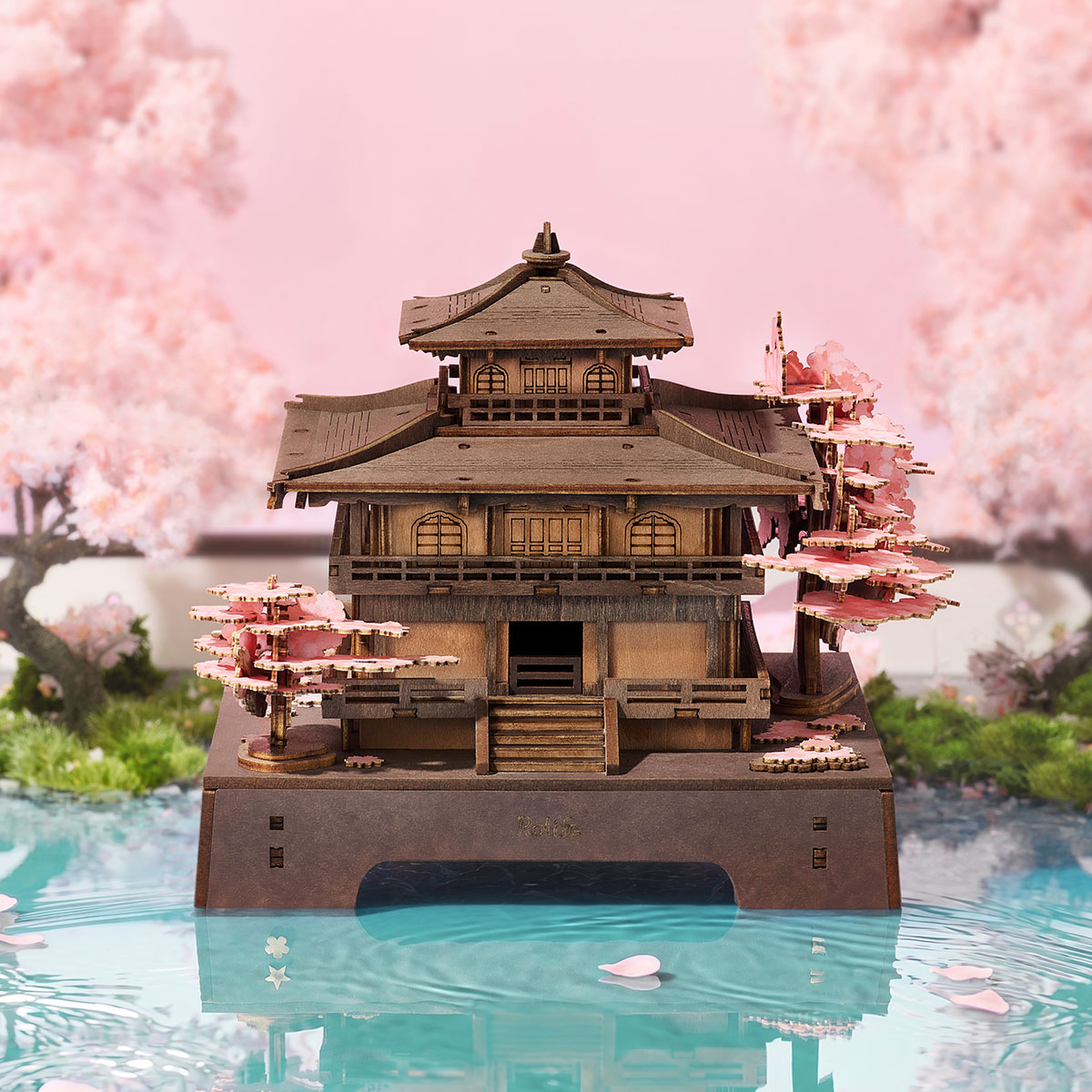Rolife Sakura Pavilion wooden puzzle displayed beside cherry blossoms and reflective water