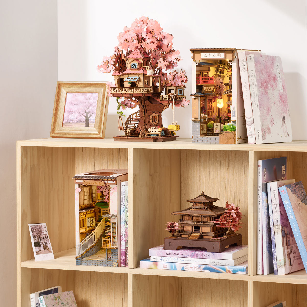 Rolife Sakura Pavilion, der auf einem Bücherregal mit Büchern und anderen Miniaturhausmodellen ausgestellt ist