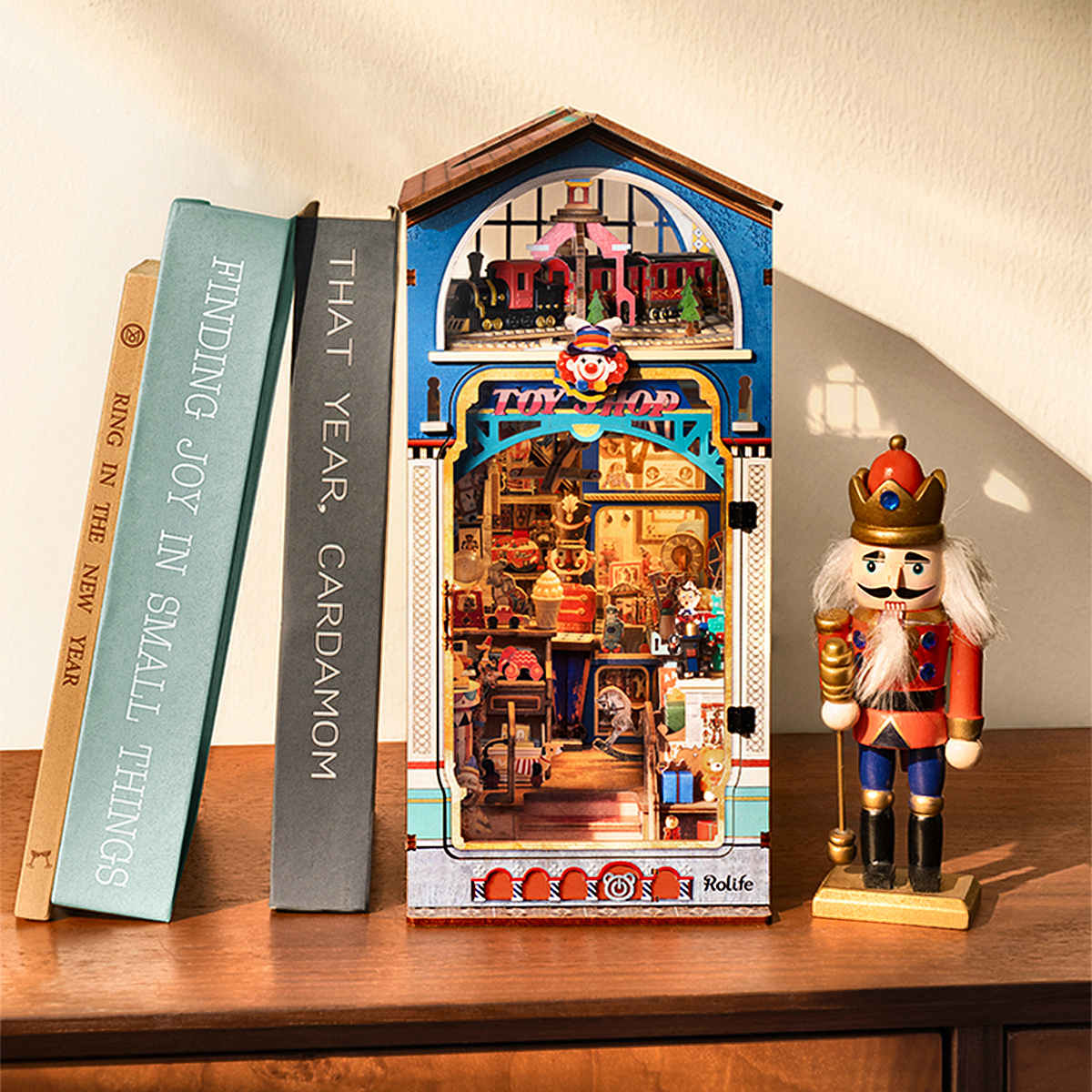 Rolife Treasure Toy Shop DIY Book Nook displayed beside books and nutcracker