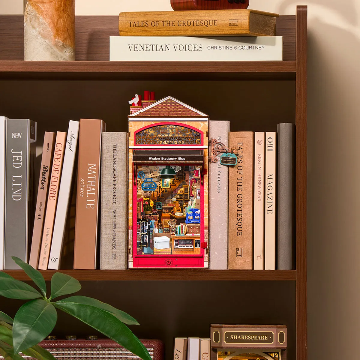 Rolife Wisdom Stationery Shop DIY Book Nook displayed between books on a bookshelf