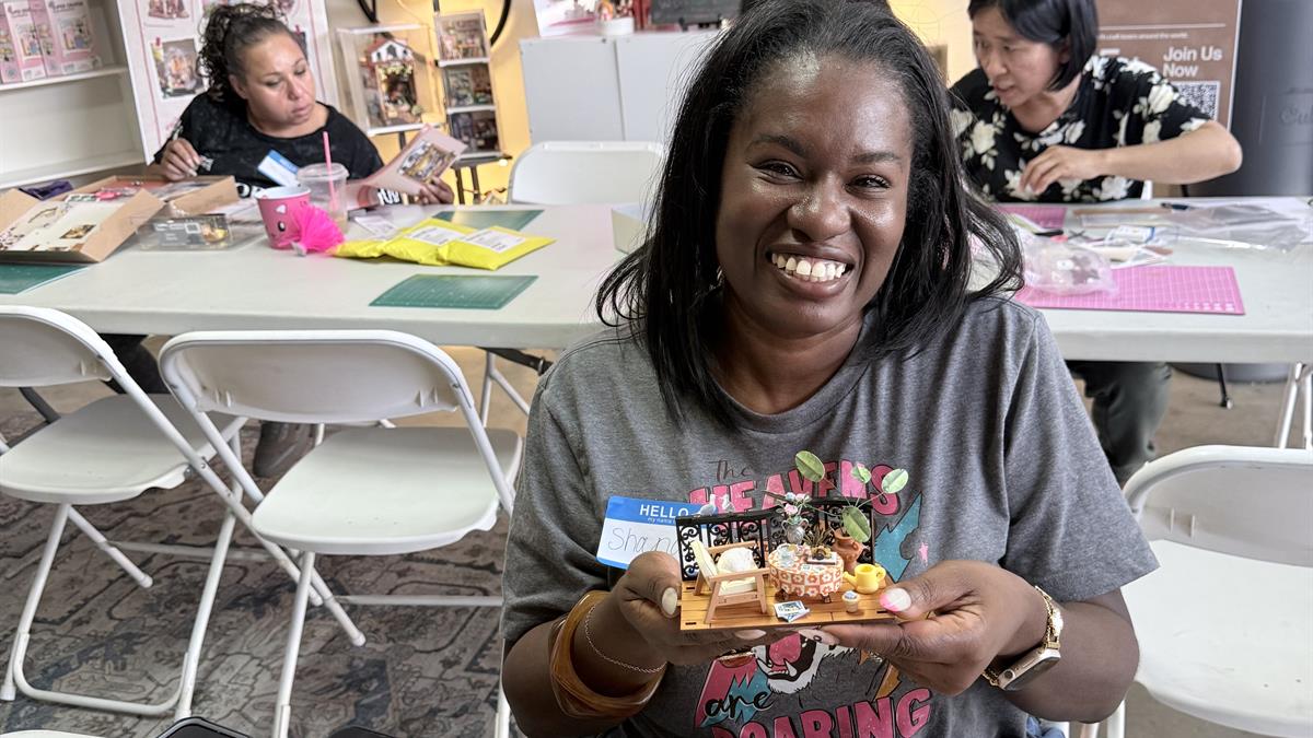 A smiling crafter holds a finished Rolife miniature at the Lake Elsinore DIY gathering