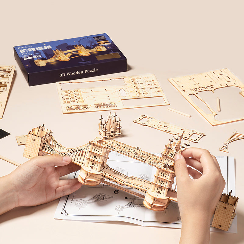 Manos construyendo el Rolife Tower Bridge TG412 con la caja y la hoja de instrucciones